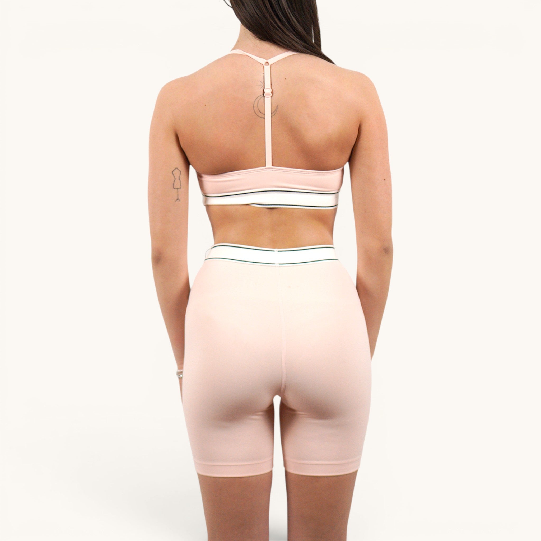 Numero 5 pink nylon-spandex sports bra and biker shorts set with white and green elastic band detail.