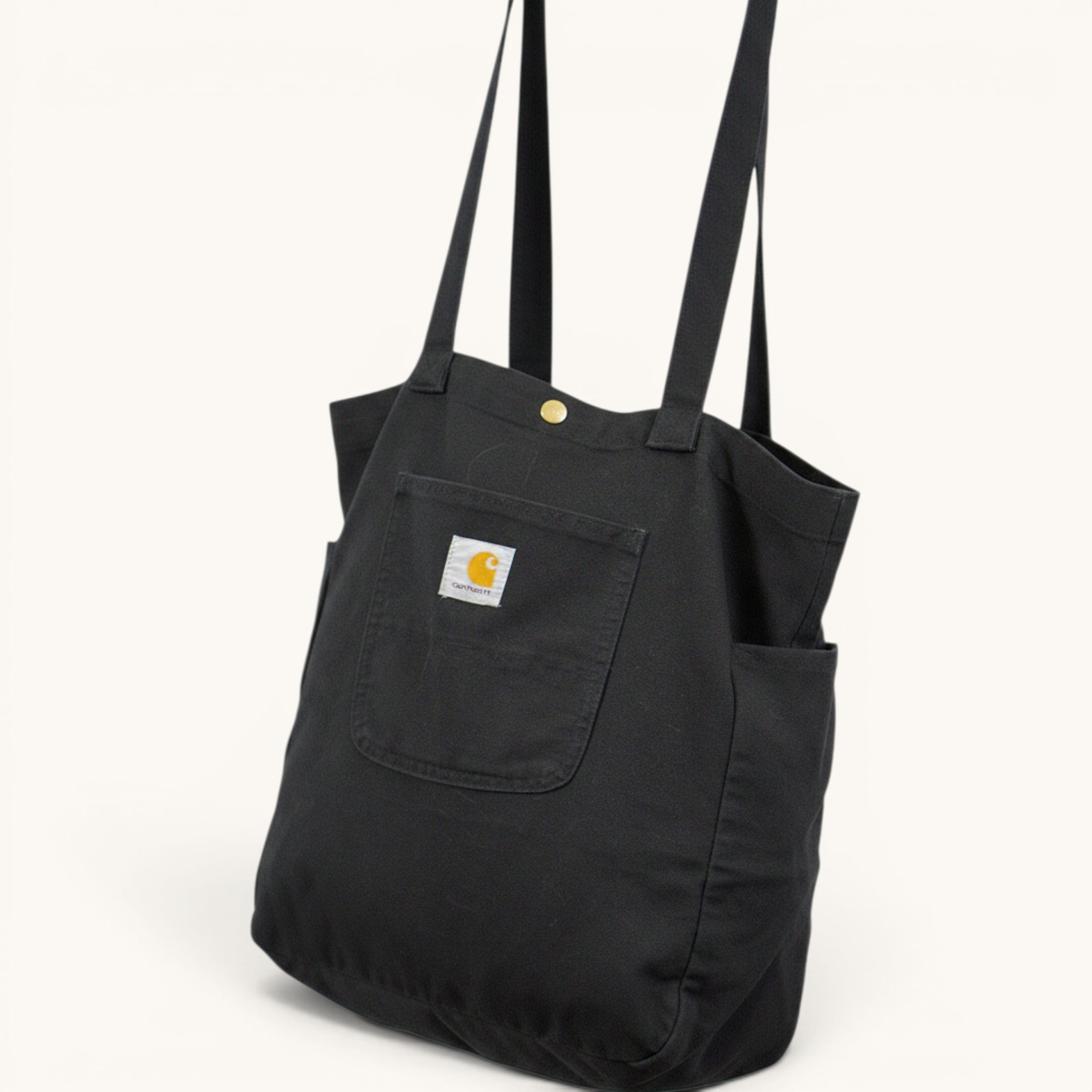 Numero 5 Borsa tote nera in tela Carhartt con tasca frontale e chiusura a bottone a pressione.
