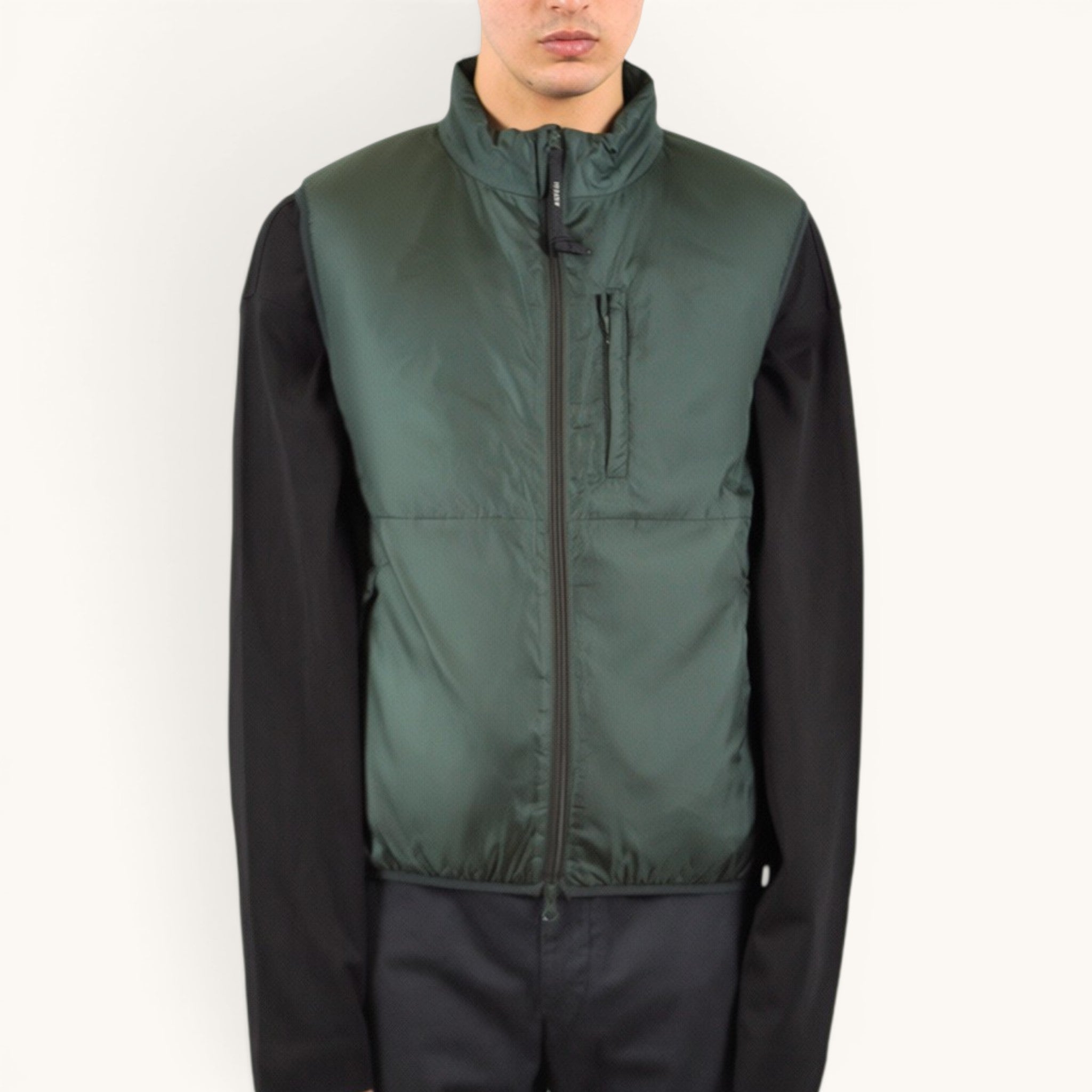 Numero 5 green quilted puffer vest with zip pockets and black long sleeves.